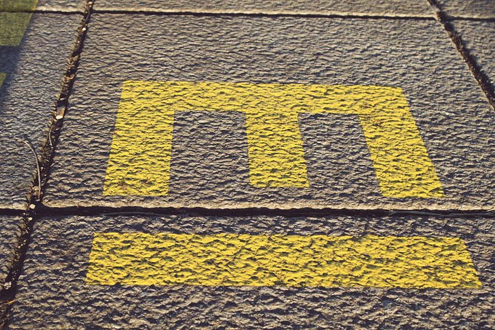 Ein gelbes Symbol in Form des Buchstabens "M" ist auf einem grobkörnigen Boden gemalt. Es deutet darauf hin, dass sich in der Nähe eine U-Bahn-Station oder Haltestelle befindet.