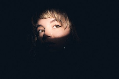 Dramatic Portrait: Woman's Face in Shadow and Light A close-up portrait of a person with light illuminating part of their face, creating a contrast against a dark background. Their gaze is directed slightly upward, conveying a sense of intrigue or contemplation.